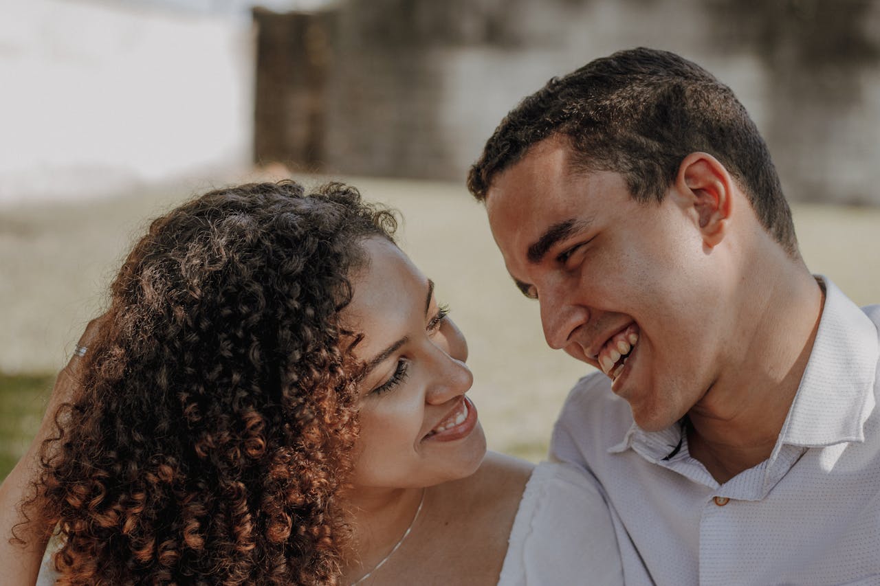 A young couple smiling and enjoying a moment together in an outdoor setting.