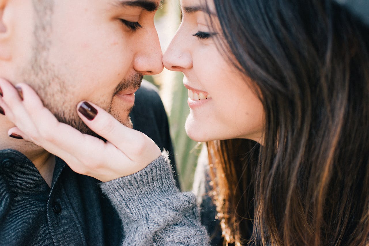 Close-up of a loving couple smiling while touching noses, expressing affection and happiness.