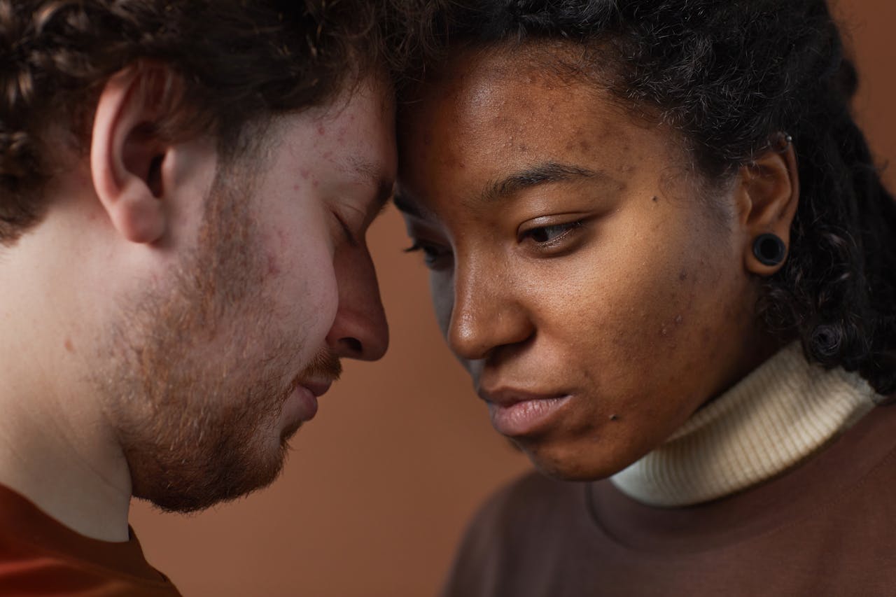 Close-up of a loving interracial couple gently touching foreheads, expressing connection and emotion.