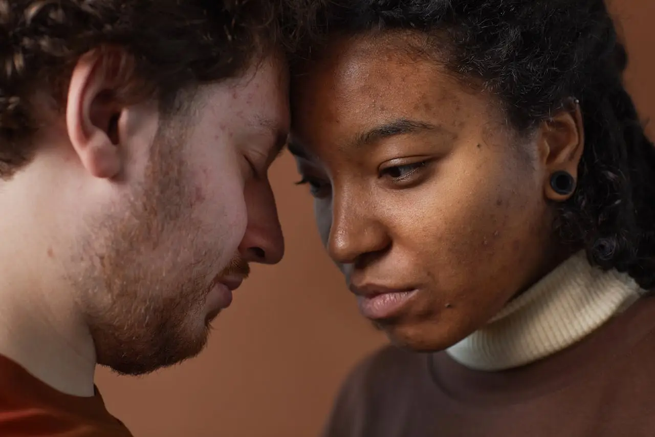 Close-up of a loving interracial couple gently touching foreheads, expressing connection and emotion.